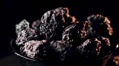 Siyah bir plaka üzerinde dönen kuru eriklerin yakın plan görüntüsü zengin doku ve koyu rengi basit bir ayarda gösterir