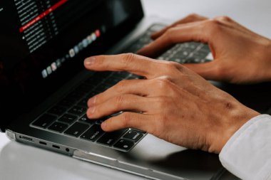 Modern ofis ortamında dizüstü bilgisayarda çalışan başarılı bir iş kadını. Arka planda hafif ışıklandırma var.