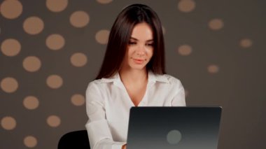 Genç bir kadın, modern bir ofis alanında bilgisayarının başında çalışırken başarıyı kutluyor.