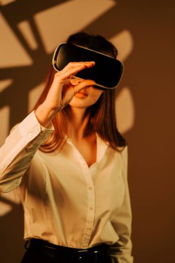 Sanal gerçeklik gözlüğü takmış, dijital dünyayı keşfeden bir kadın ilginç bir deneyimde renkli bir arka plana karşı çıkıyor.