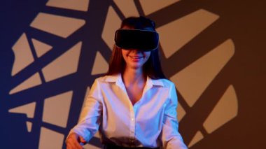 Kadın, canlı bir dijital ortamda sanal gerçeklik gözlüğü takarken büyüleyici bir teknolojiyle meşgul oluyor.