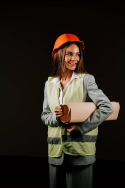 Woman engineer wearing safety gear and helmet, smiling confidently on a black background clipart