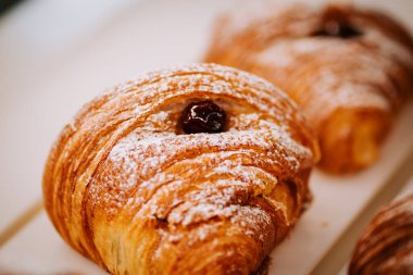 Sabahın köründe sıcak bir kahve dükkanının tezgahında taze pişmiş kruvasanlar sergileniyor.