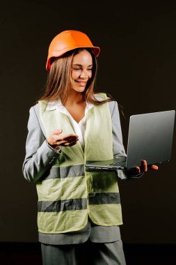 Güvenilir kadın mühendis, karanlık bir arka planda dizüstü bilgisayarıyla çatışmaya giriyor.