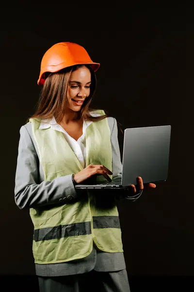 Güvenilir kadın mühendis, karanlık bir arka planda dizüstü bilgisayarıyla çatışmaya giriyor.