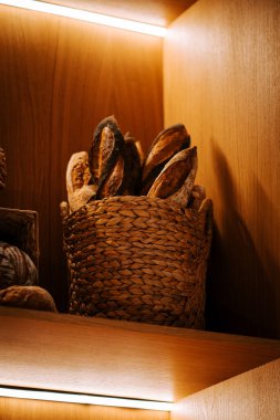 Freshly baked bread displayed on wooden shelves in a cozy store setting clipart