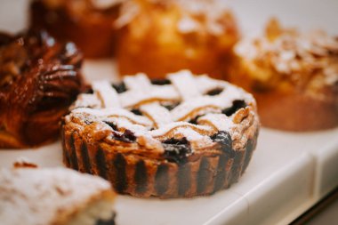 Delicious cakes displayed in a pastry shop showcasing a variety of flavors during a bustling afternoon clipart