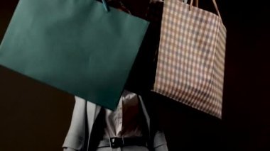 Alışveriş merkezinde şık giysiler içinde alışveriş yapan bir kadın elinde bir sürü renkli çanta tutuyor.