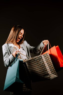 Alışveriş deneyiminden zevk alan bir kadın, kapalı bir alışveriş çılgınlığı sırasında şık kıyafetler içinde bir sürü çantasıyla.