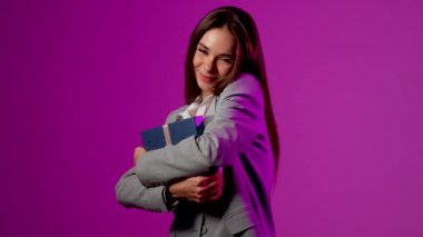 Heyecanlı kadın canlı bir sunum sırasında canlı mor arka plana karşı sürpriz bir hediye açıyor.