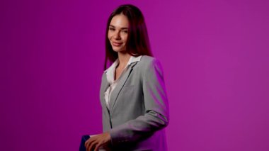 Heyecanlı kadın canlı bir sunum sırasında canlı mor arka plana karşı sürpriz bir hediye açıyor.