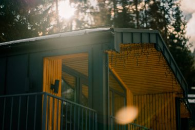 Kış mevsiminde ahşap aksanlı modern mimarinin yer aldığı dağ manzarası, karla kaplı arazi ve ormanları gözler önüne seriyor