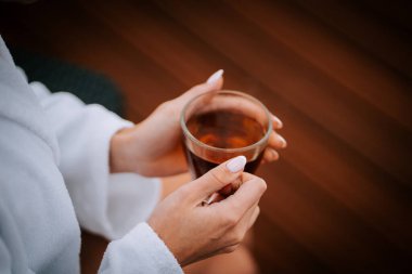 Beyaz cüppeli kadın, sakin bir sabah boyunca terasta karla kaplı dağlarla çay içmeyi sever.