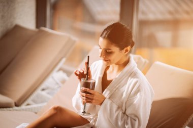 Kokteylle kaplıcada dinlenen bir kadın huzur ve gençliğin tadını çıkarıyor.