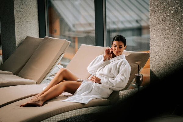 Женщина отдыхает в спа-центре с коктейлем, наслаждаясь спокойствием и омоложением в спокойной обстановке