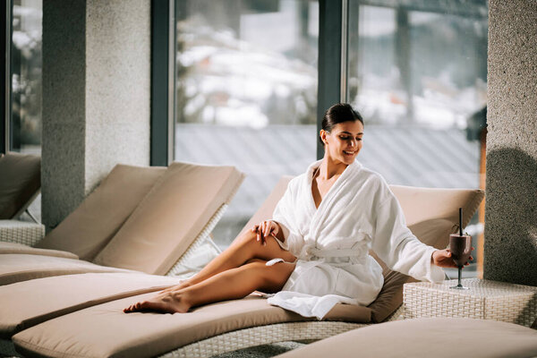 Женщина отдыхает в спа-центре с коктейлем, наслаждаясь спокойствием и омоложением в спокойной обстановке