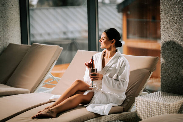 Женщина отдыхает в спа-центре с коктейлем, наслаждаясь спокойствием и омоложением в спокойной обстановке