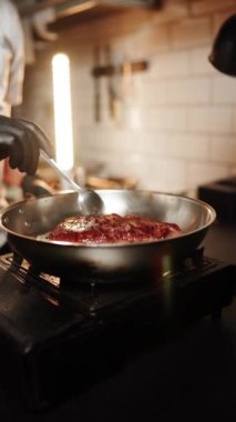 Sıcak bir mutfak ortamında kömür ızgarasında leziz bir biftek pişiriyorum.