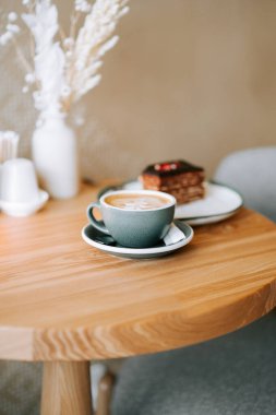 Öğleden sonra dinlenme zamanı, rahat bir kafede, ahşap bir masanın üzerinde kahve ve kek.