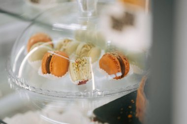 Colorful macarons displayed under a glass dome in a cozy bakery  clipart