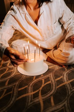 Doğum gününü evde pasta ve mumlarla kutlayan bir kadın.