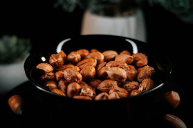 Siyah bir tabağa dizilmiş fındıklar ve zıt bir arka plan.