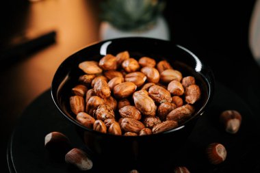 Siyah bir tabağa dizilmiş fındıklar ve zıt bir arka plan.