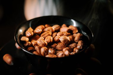 Siyah bir tabağa dizilmiş fındıklar ve zıt bir arka plan.