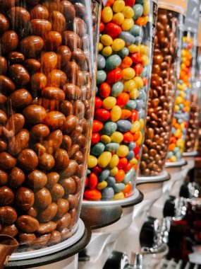 Öğleden sonra yerel bir şekerci dükkanında çeşitli şekerlerle dolu renkli şeker kutuları.