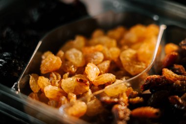 Kuru üzümler bir tabakta sanatsal olarak sıralanmış altın ve siyah çeşitlerle siyah bir kasede.