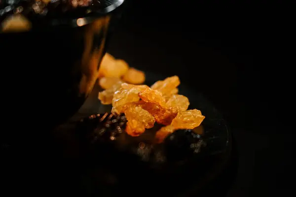 Kuru üzümler bir tabakta sanatsal olarak sıralanmış altın ve siyah çeşitlerle siyah bir kasede.