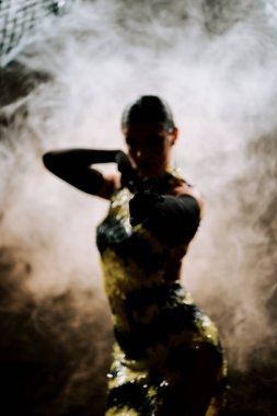 Şehvetli Latin dansçı dumanlı atmosferde dramatik ışıklandırma ile Latin dansına olan tutkusunu ve yeteneğini gösteriyor.