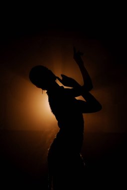 Şehvetli Latin dansçı dumanlı atmosferde dramatik ışıklandırma ile Latin dansına olan tutkusunu ve yeteneğini gösteriyor.