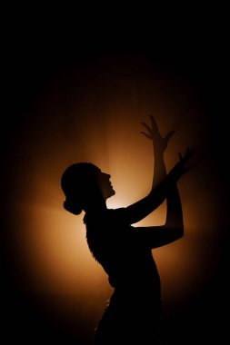 Şehvetli Latin dansçı dumanlı atmosferde dramatik ışıklandırma ile Latin dansına olan tutkusunu ve yeteneğini gösteriyor.