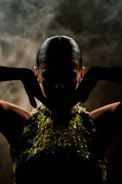 Şehvetli Latin dansçı dumanlı atmosferde dramatik ışıklandırma ile Latin dansına olan tutkusunu ve yeteneğini gösteriyor.