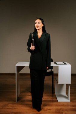 Modern ofis ortamında kendine güvenen bir gülümsemeyle dizüstü bilgisayarda çalışan profesyonel bir kadın.