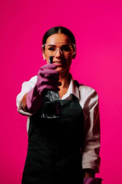 Portrait of a confident female cleaner wearing gloves against a vibrant pink background showcasing her dedication to cleanliness clipart