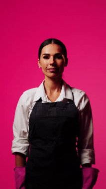 Canlı pembe arka planda aletlerle temizlik yapan kadın ev temizleme konsepti ve profesyonelliği gösteriyor.