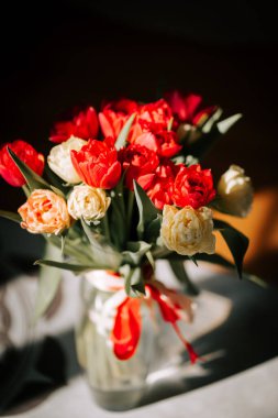 Temiz bir vazodaki parlak laleler güneşli bir odaya yansıyarak baharın gelişinin özünü yansıtıyor.