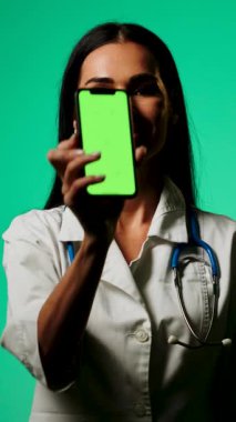 Doktor, profesyonel bir ortamda yeşil ekranlı bir akıllı telefon kullanarak tıbbi bilgileri gösteriyor.