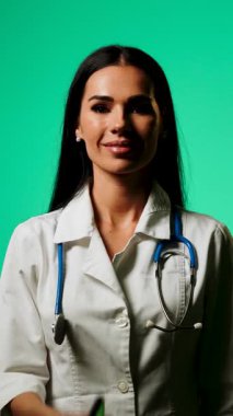 Doktor, profesyonel bir ortamda yeşil ekranlı bir akıllı telefon kullanarak tıbbi bilgileri gösteriyor.