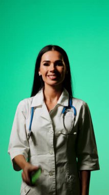 Doktor, profesyonel bir ortamda yeşil ekranlı bir akıllı telefon kullanarak tıbbi bilgileri gösteriyor.