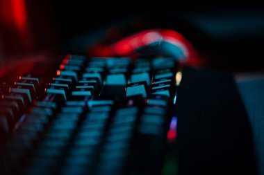 Bir bilgisayar faresi ve klavyeyi koyu ışıkta gösteren neon aksanlı oyun ayarları