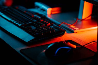 Bir bilgisayar faresi ve klavyeyi koyu ışıkta gösteren neon aksanlı oyun ayarları