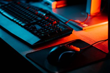 Bir bilgisayar faresi ve klavyeyi koyu ışıkta gösteren neon aksanlı oyun ayarları