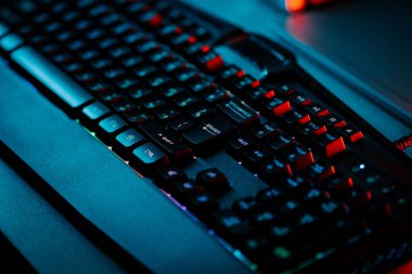 Bir bilgisayar faresi ve klavyeyi koyu ışıkta gösteren neon aksanlı oyun ayarları