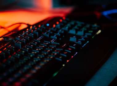 Bir bilgisayar faresi ve klavyeyi koyu ışıkta gösteren neon aksanlı oyun ayarları