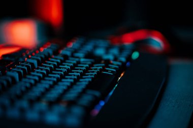 Bir bilgisayar faresi ve klavyeyi koyu ışıkta gösteren neon aksanlı oyun ayarları