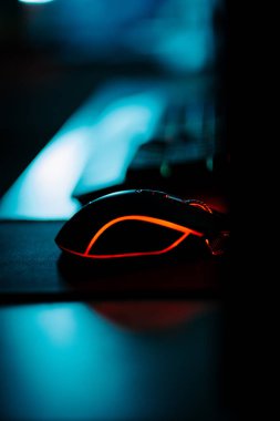 Bir bilgisayar faresi ve klavyeyi koyu ışıkta gösteren neon aksanlı oyun ayarları