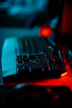 Bir bilgisayar faresi ve klavyeyi koyu ışıkta gösteren neon aksanlı oyun ayarları